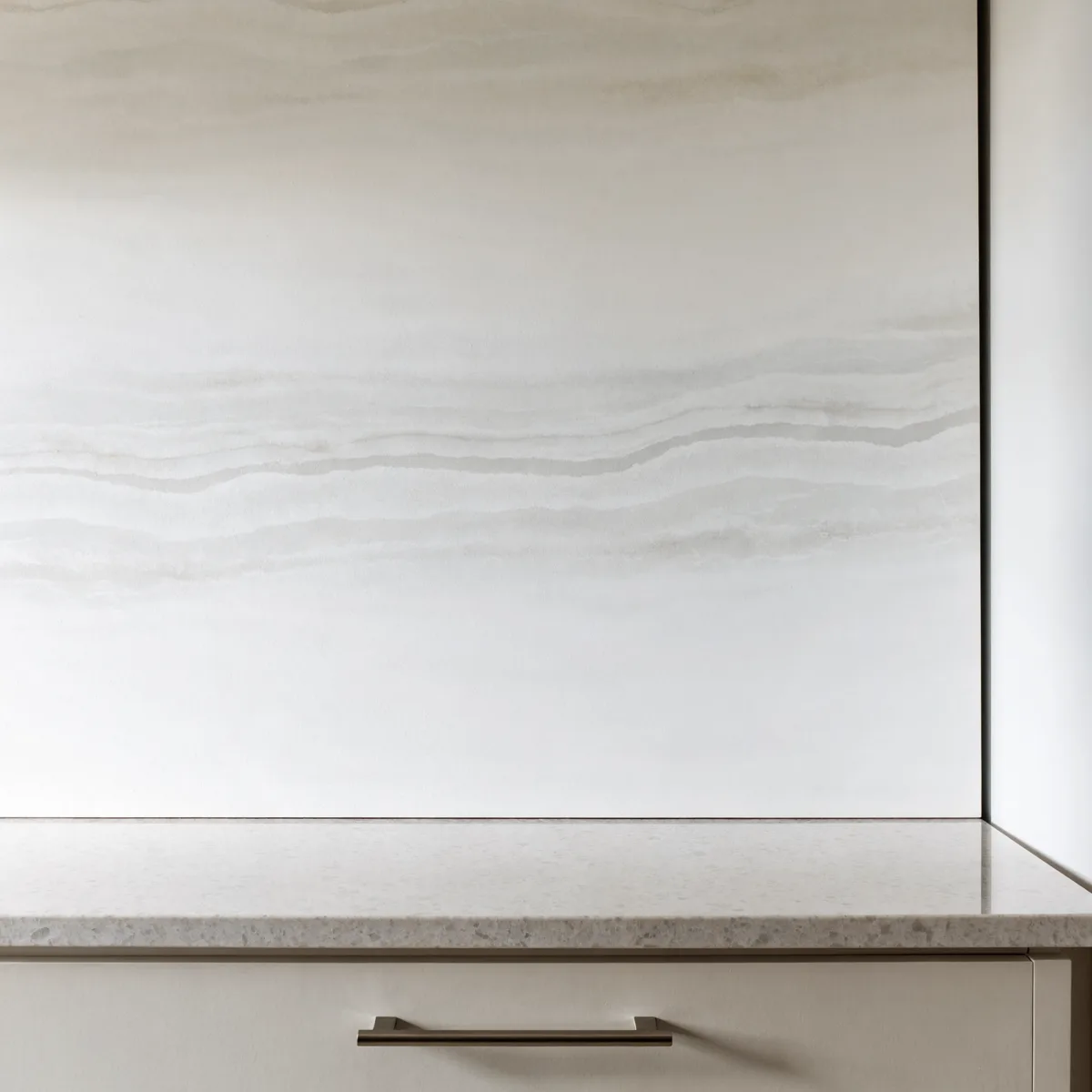 One large porcelain panel covering the wall above the counter as a single piece, its veining running unbroken across the whole width
