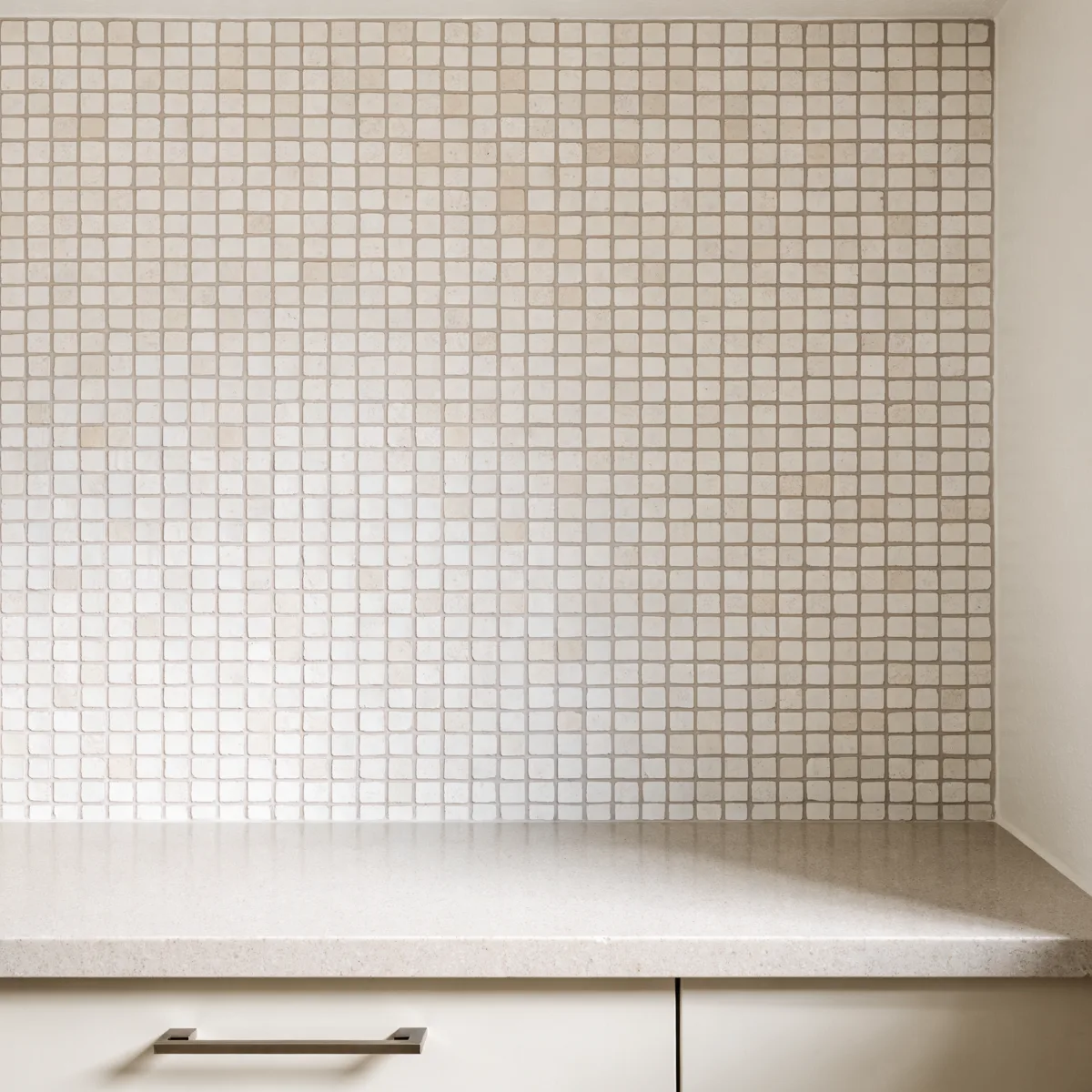 A wall of small square mosaic tile above a Davie kitchen counter, the grout lines forming a dense grid across the whole field