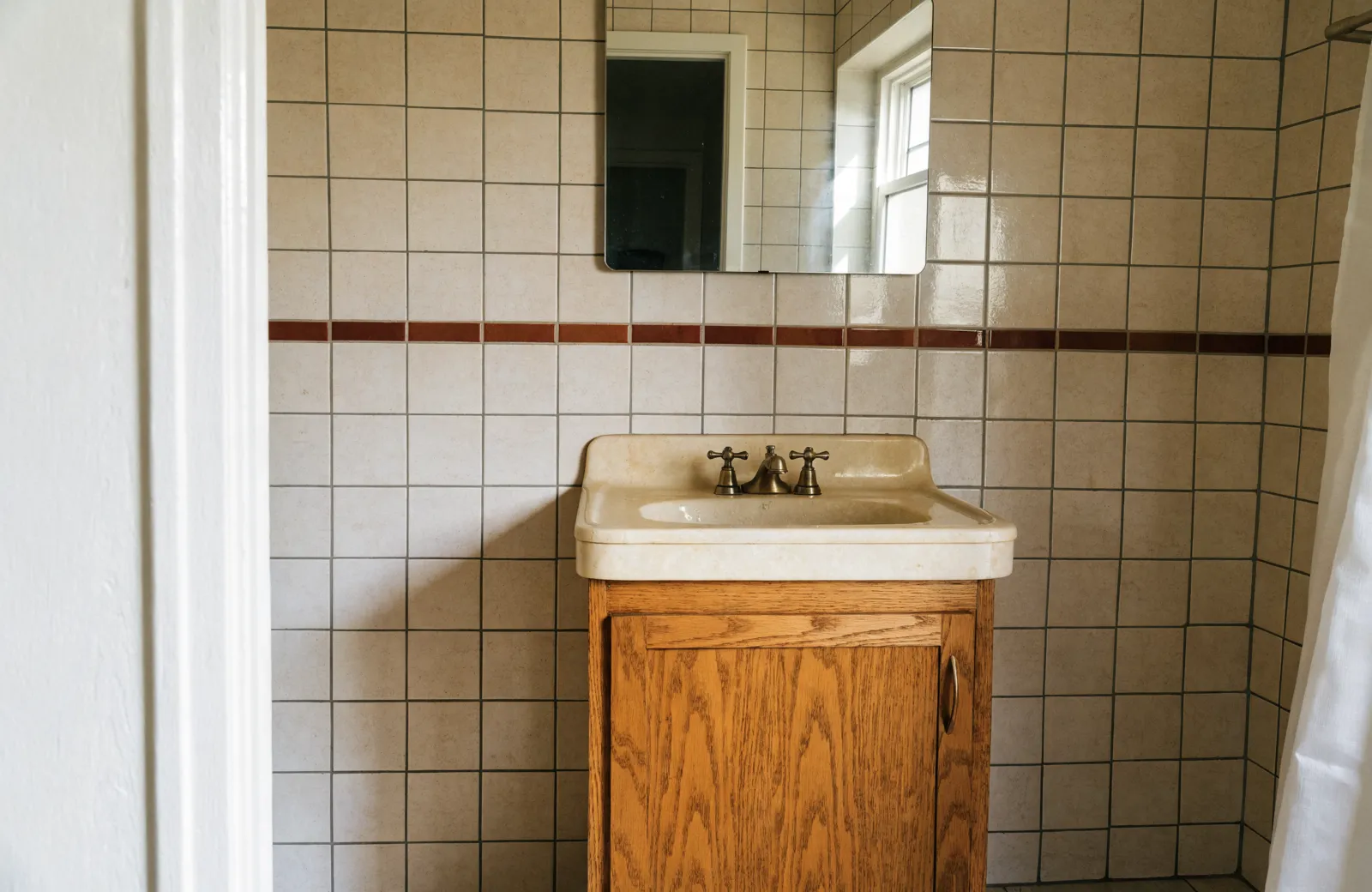 An original 1980s Davie bathroom in daily use, with a single-door builder vanity, a cultured marble top and a brass faucet