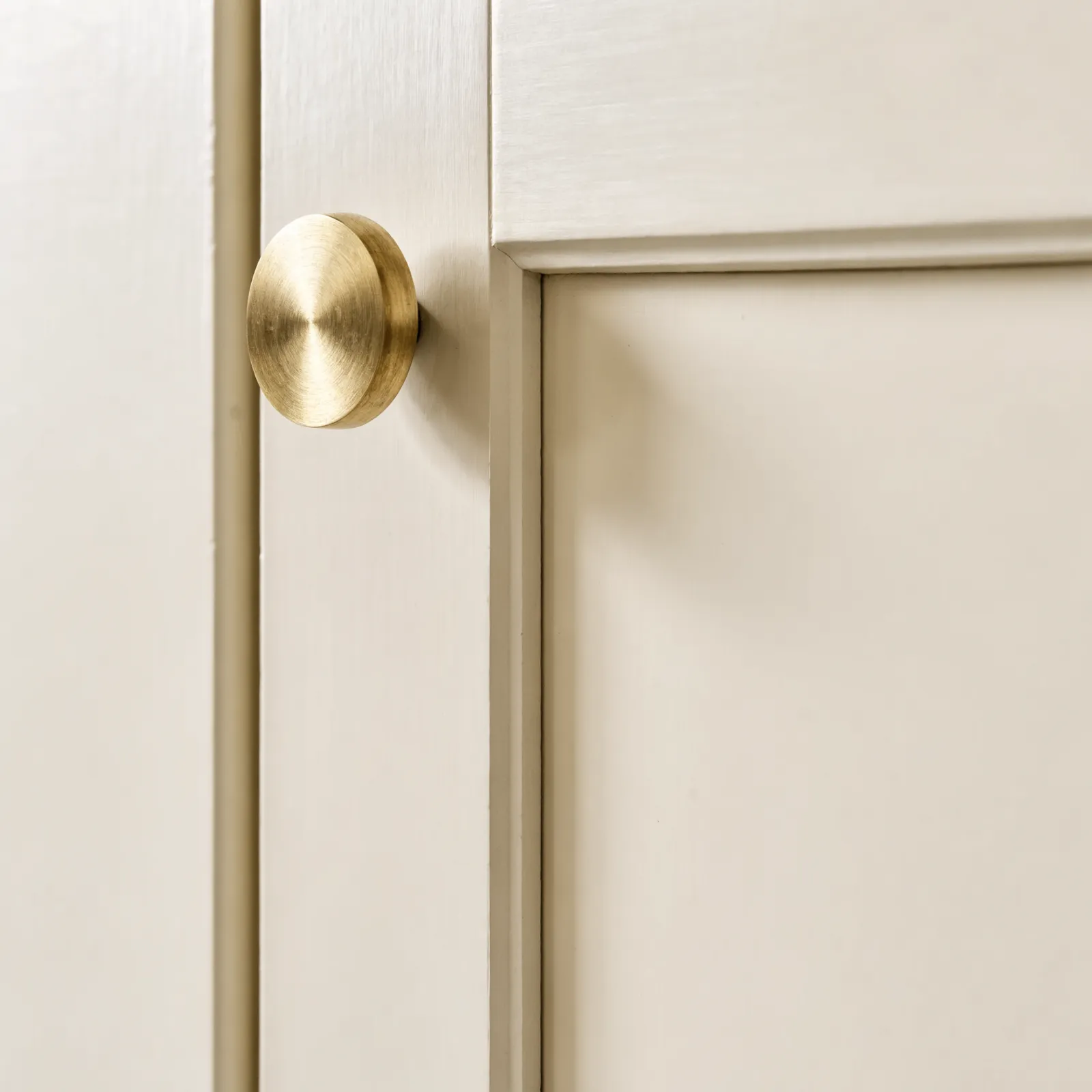A single cabinet knob on a painted shaker door, fixed through one hole in the corner of the stile