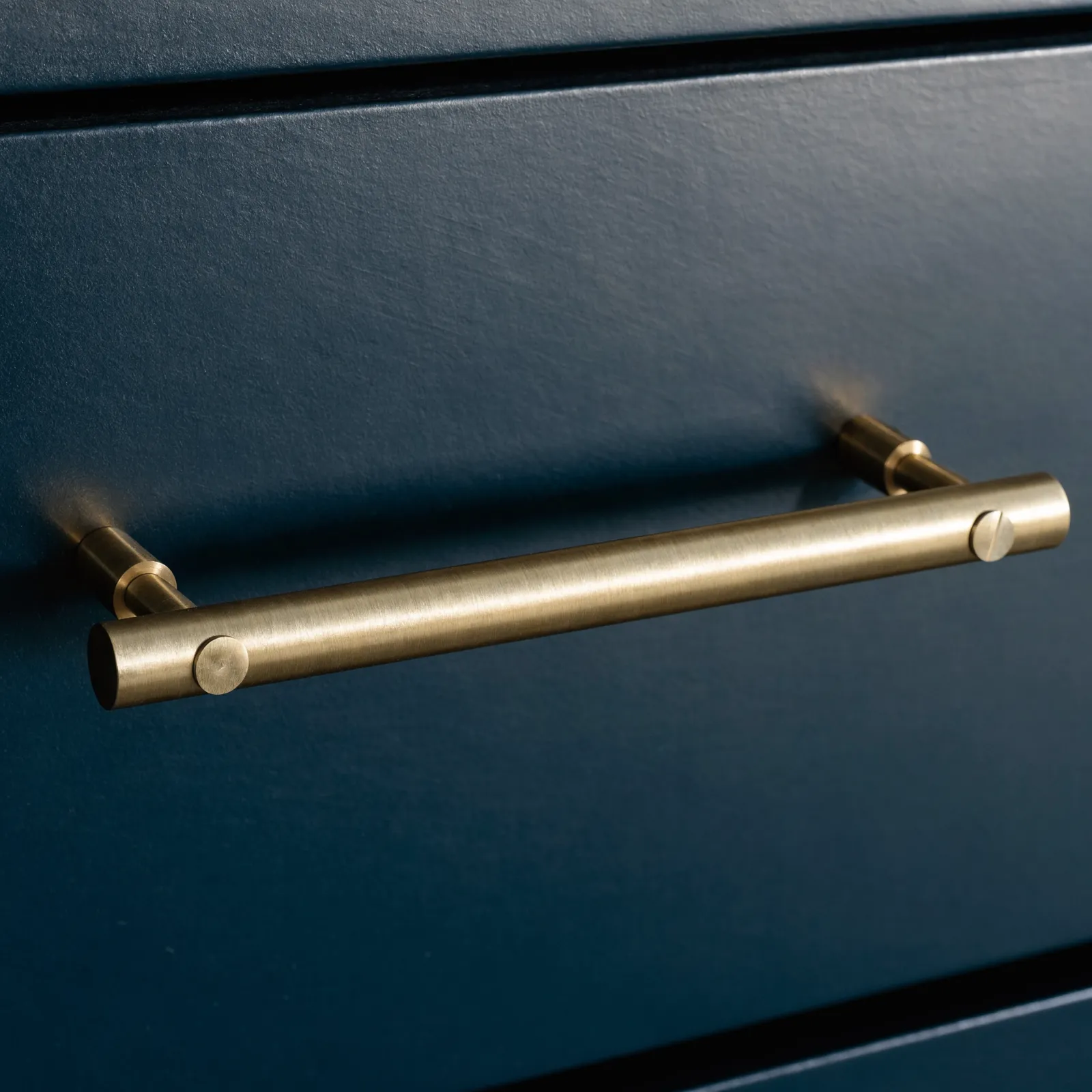A long bar pull mounted horizontally across a wide drawer front, both screws seated flush