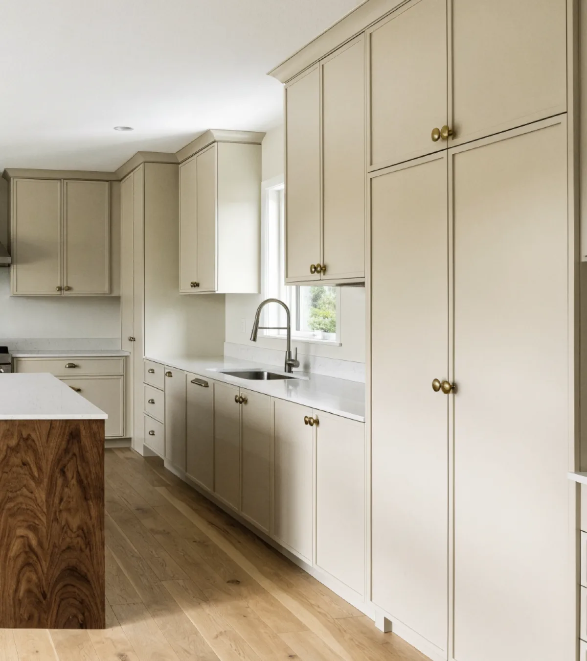 Cabinet maker near Flamingo Gardens in Davie: a long finished run of painted cabinet fronts carrying past an island to a floor to ceiling pantry wall