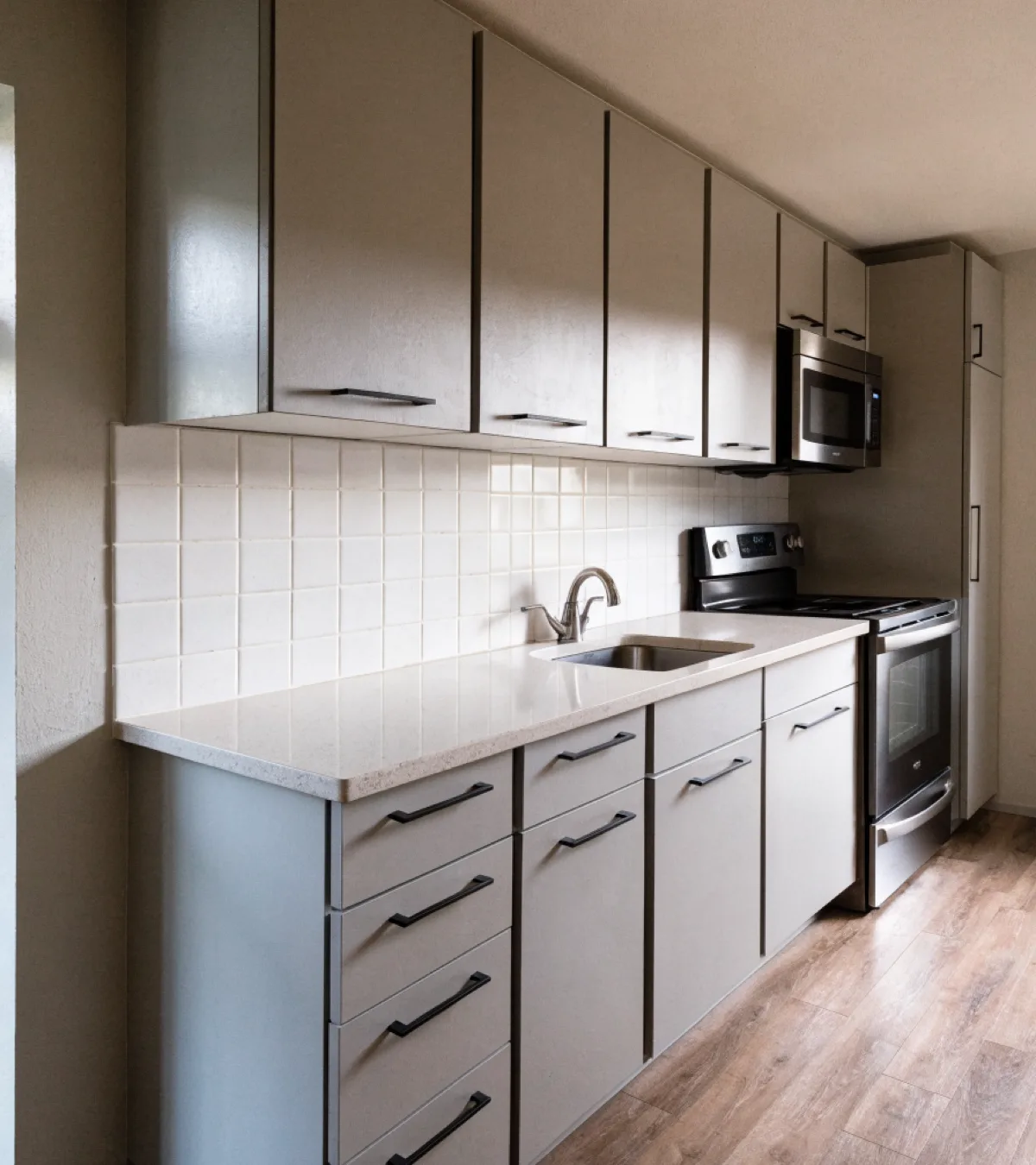 Cabinet maker near Nova Southeastern University in Davie: a finished single wall cabinet run in a condominium kitchen, flat painted fronts, plywood boxes and bar pulls