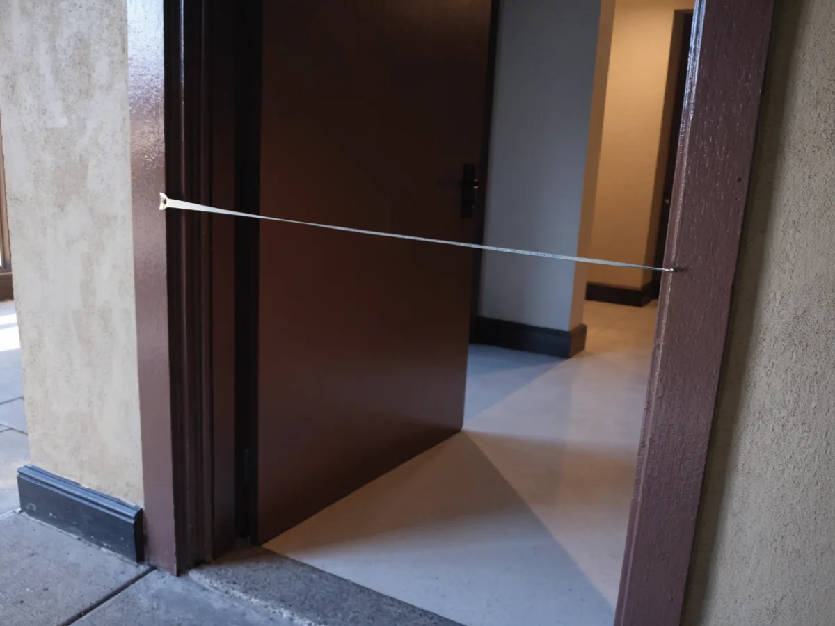 A steel tape measure hooked on the frame of an open unit door in Davie, reading the clear width of the opening