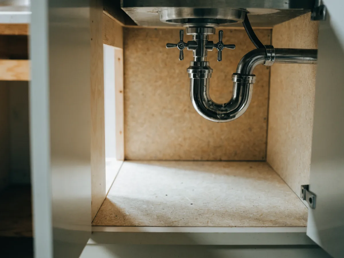 The open interior of a kitchen sink base cabinet near Pine Island Ridge in Davie, the back corner of the cabinet floor dry and sound under the trap