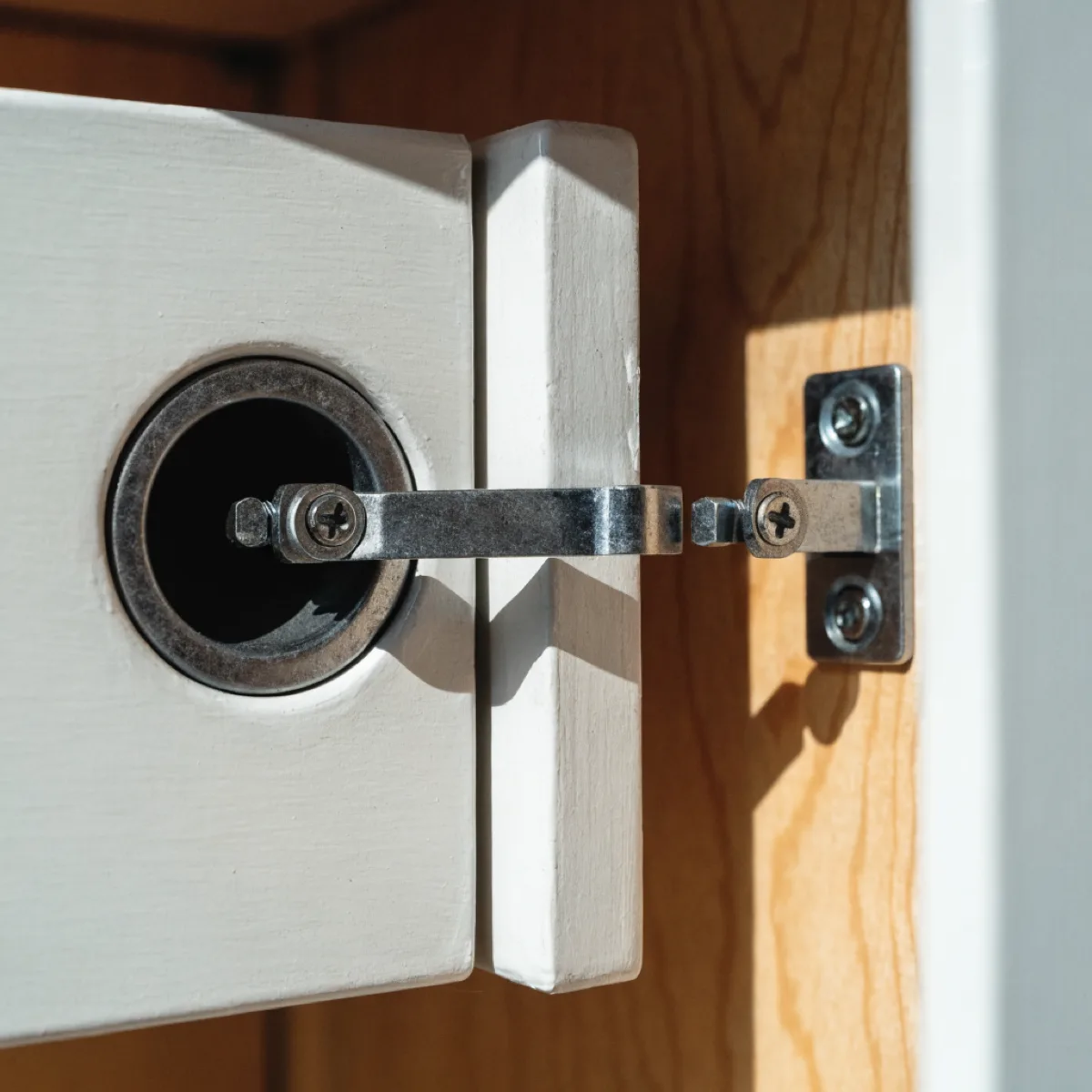 An adjustable cup hinge on a newly hung door in that same kitchen, the regulating screw visible at the mounting plate