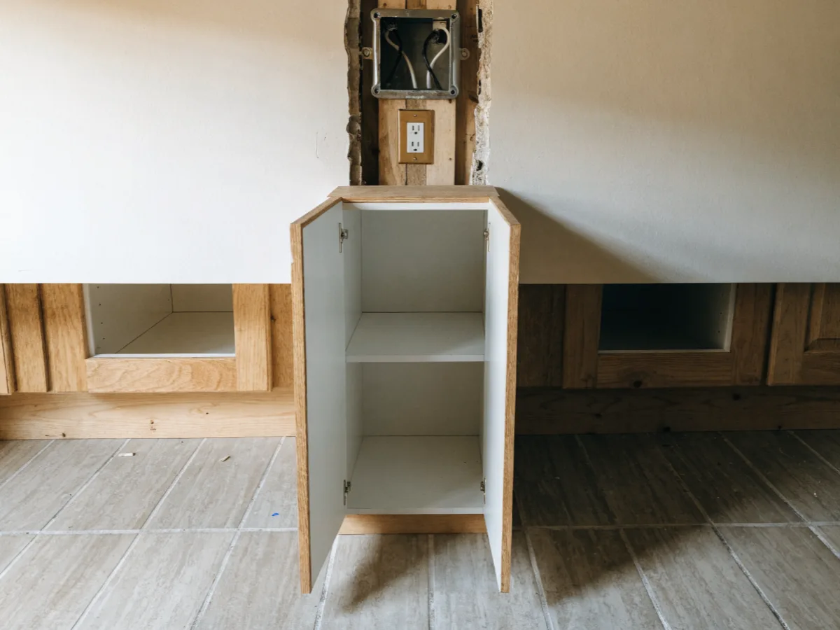 A wall cabinet pulled away from the wall in a west Davie kitchen, the junction box and receptacle exposed behind it with the wiring dressed