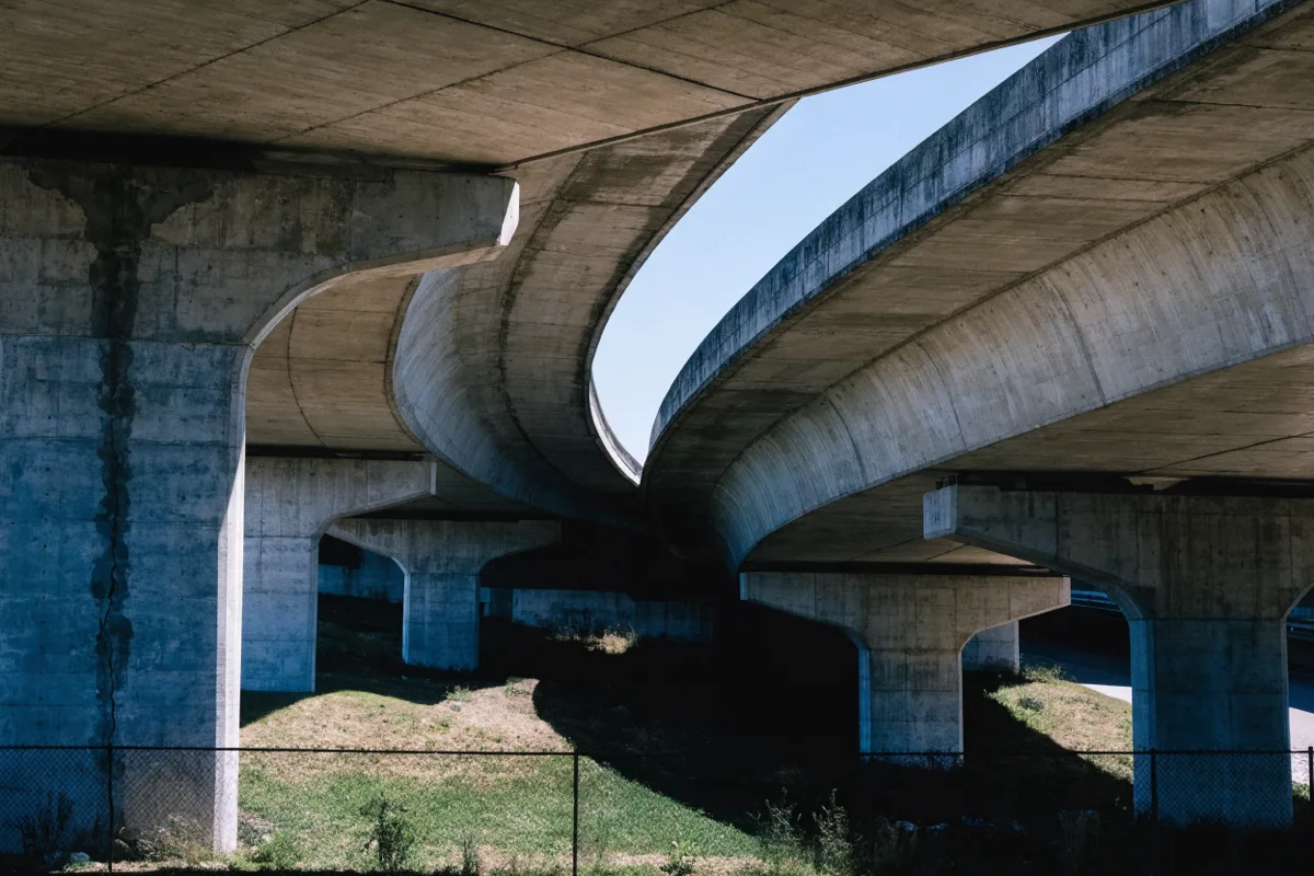 The I-595 and I-75 interchange seen from below, concrete piers and open sky, with no legible signage