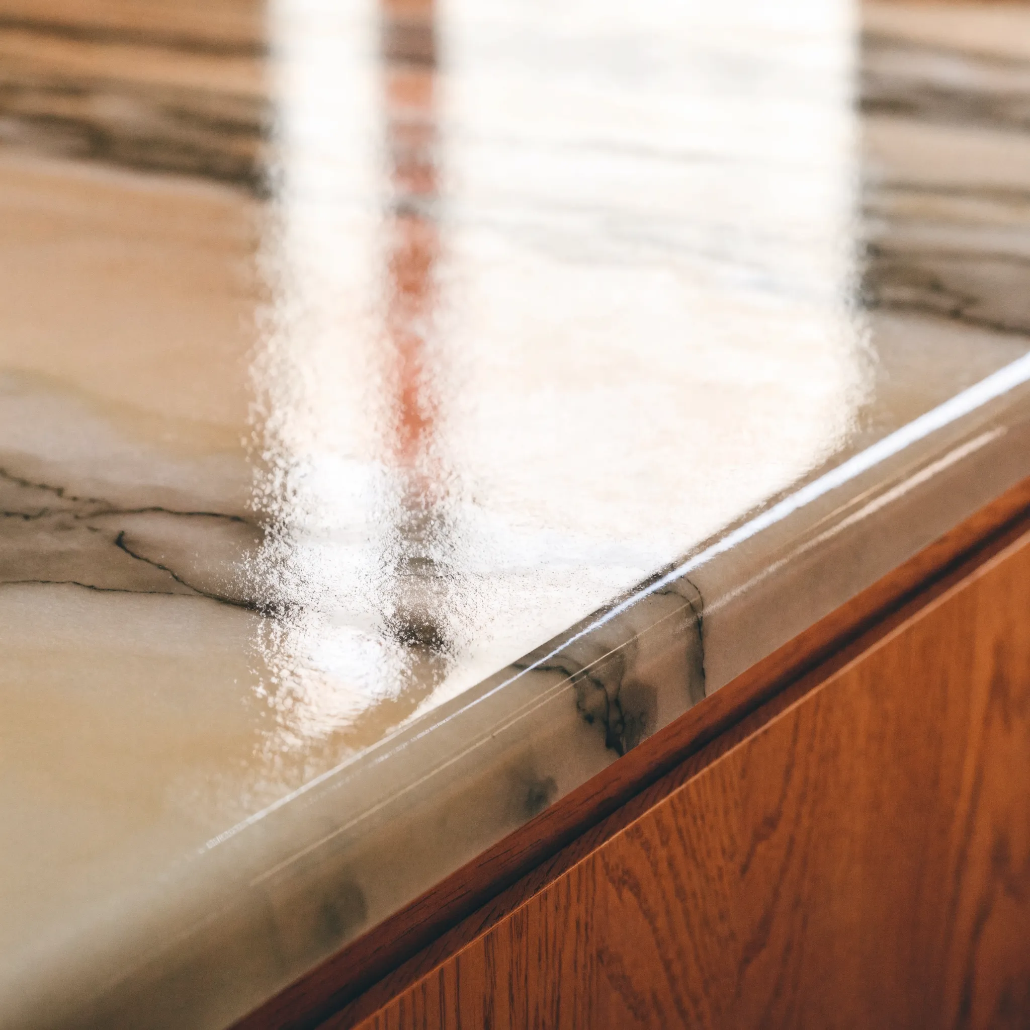 A resin coating flowing out flat across a counter surface, the stone-look veining pulled through it while it is still wet