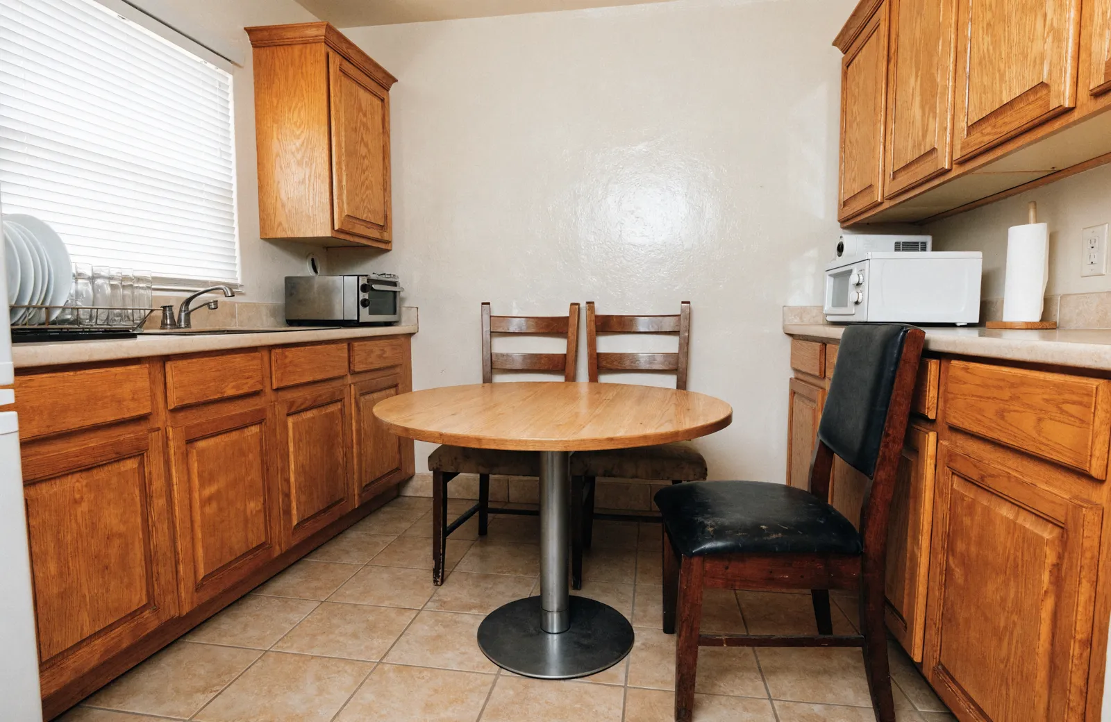 A 1987 Davie eat-in kitchen with a round table pushed into the corner, two chairs against the wall and no room to pull the third one out