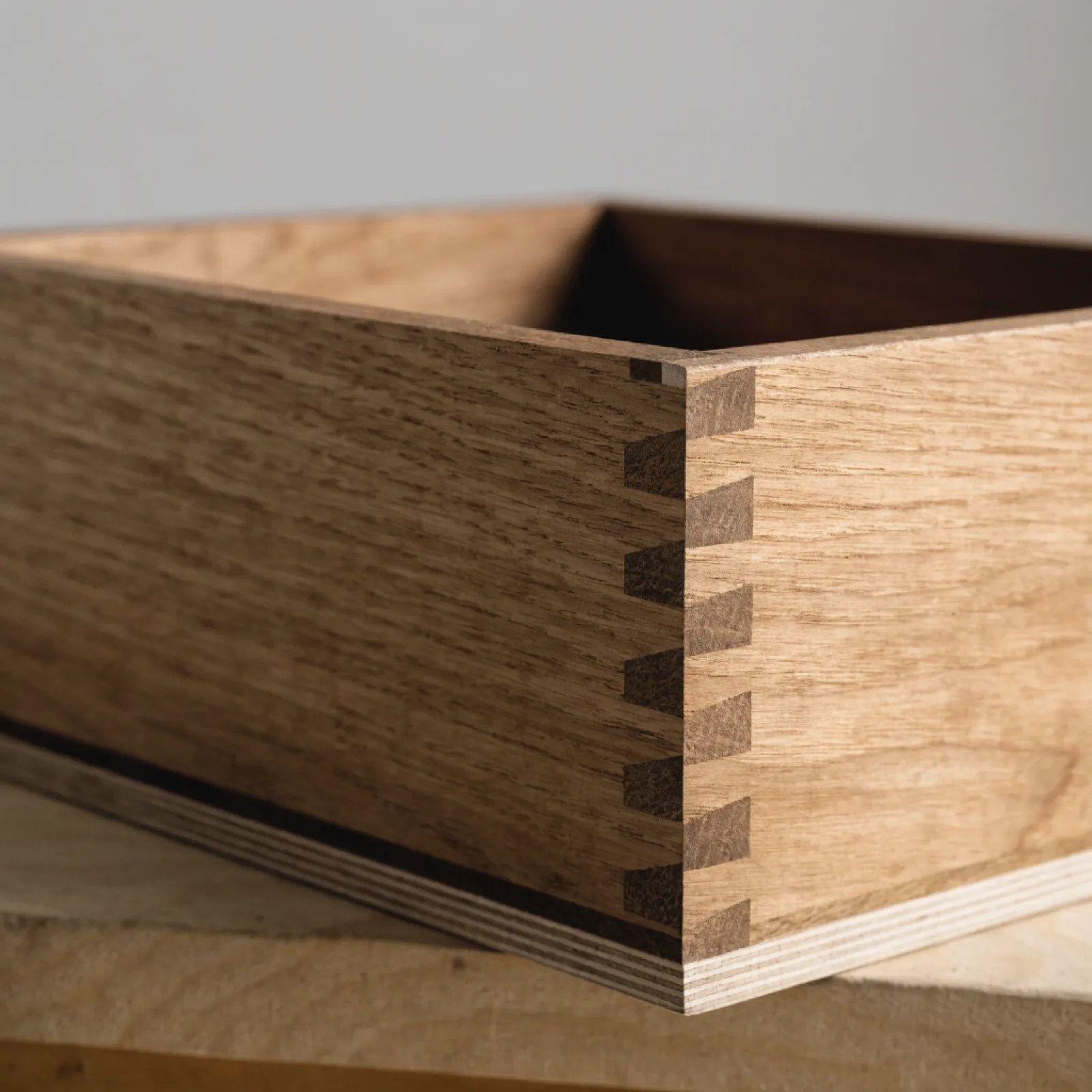 A drawer box with solid wood sides and dovetailed corners, its plywood bottom seated in a groove on four sides