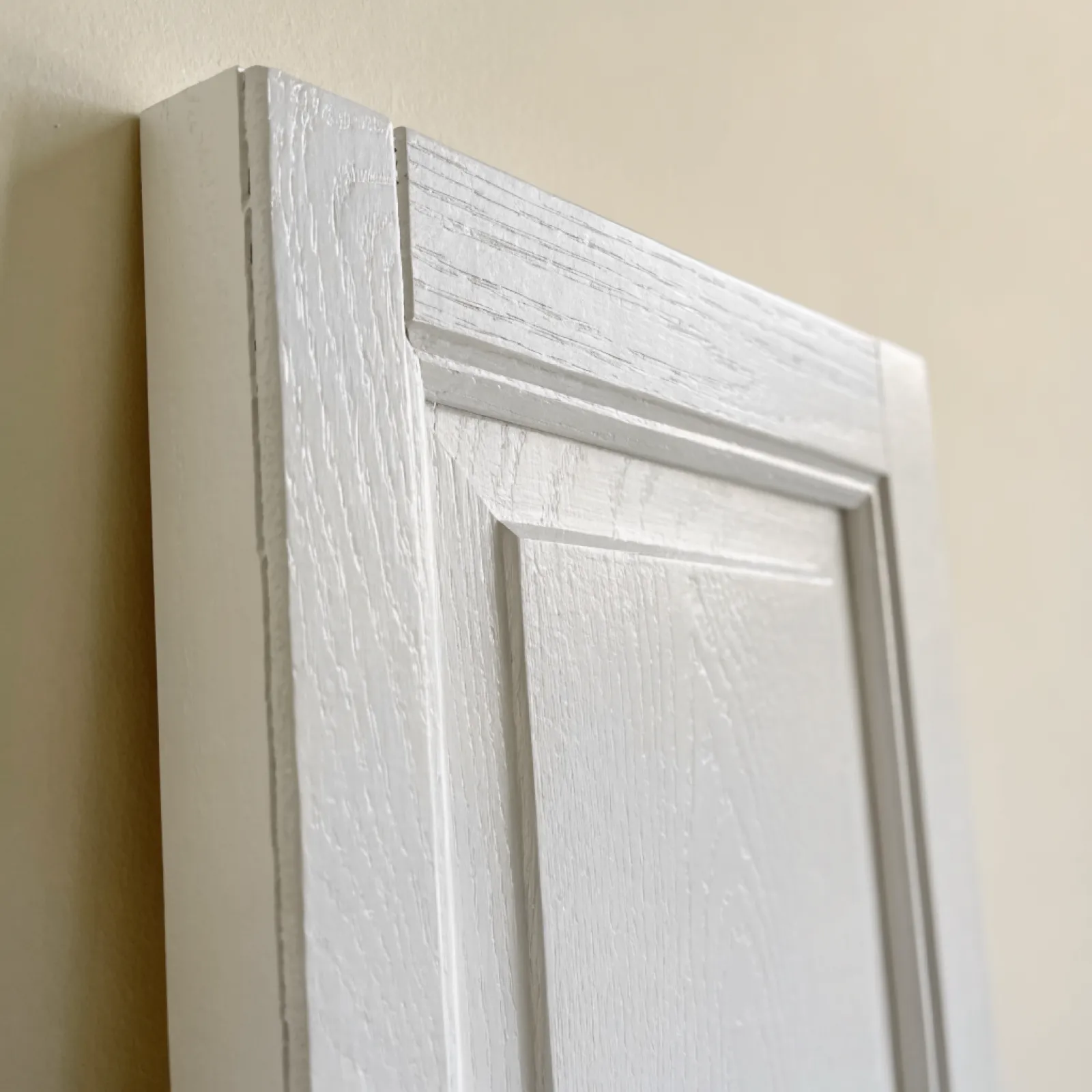 A five-piece painted door built from solid stock, the joint between the top rail and the stile reading at the corner