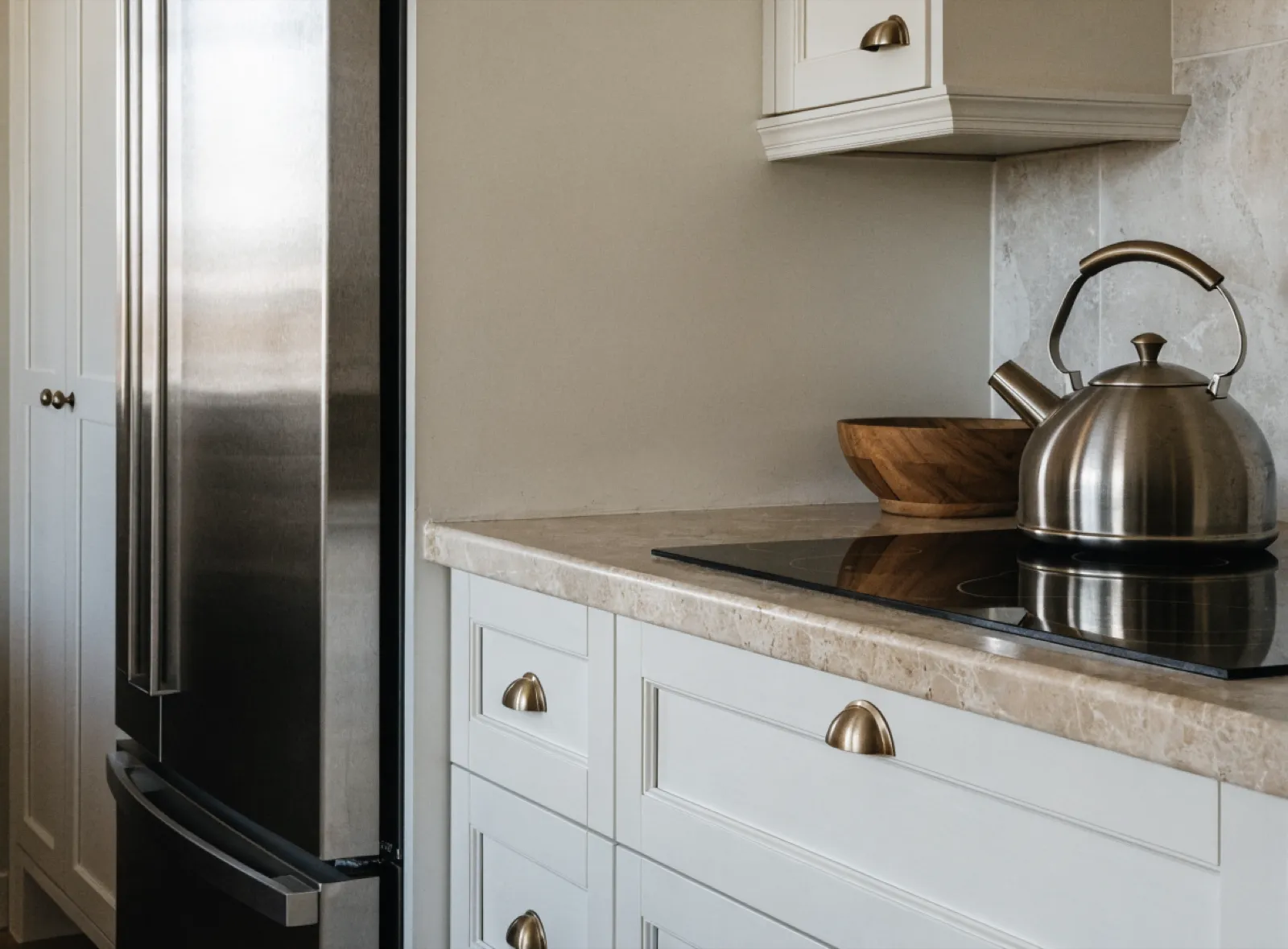 Custom kitchen cabinets in Davie, FL: a bank of drawers under the cooktop with a stone counter, and a full height pantry next to the refrigerator