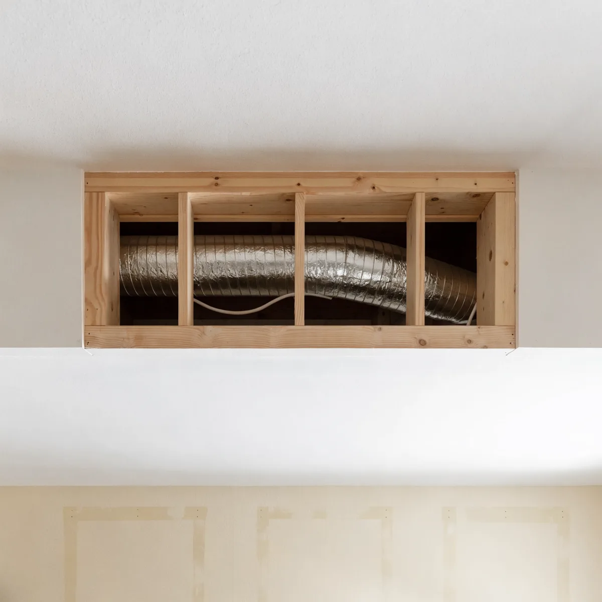 The soffit above the wall cabinets in a Davie kitchen opened up, a round flexible duct and a cable running through the framing inside it
