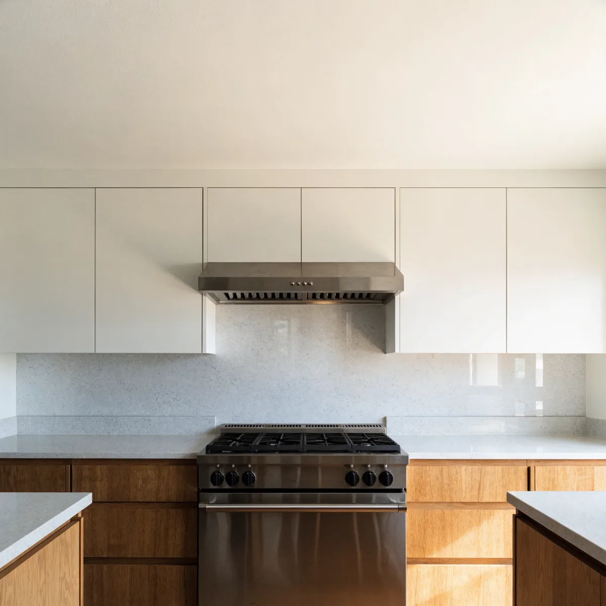 A slide-in range set between two equal runs of counter with the hood above it and the slab backsplash behind