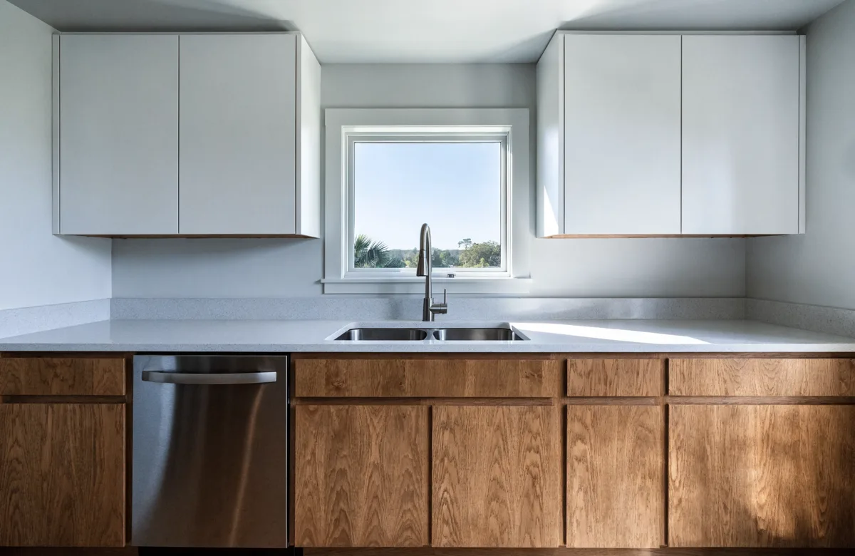 The sink zone of that Davie kitchen seen straight on, the undermount sink set into the counter under the window with the dishwasher beside it