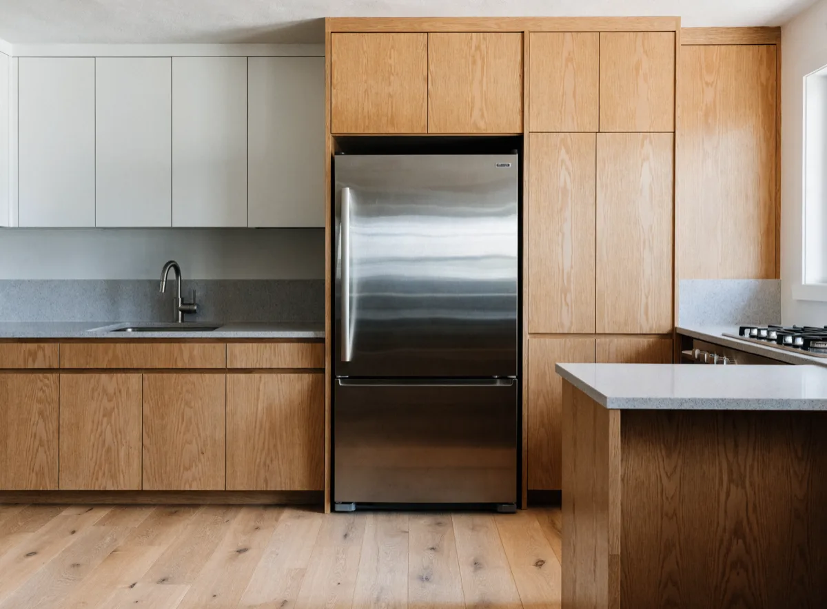The refrigerator standing flush in its cabinet niche with a short landing counter immediately beside it