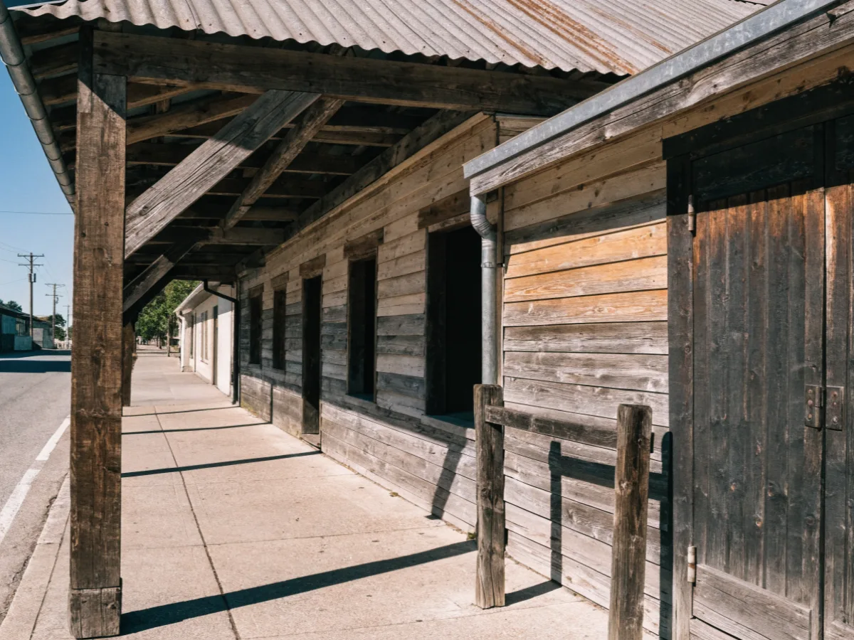 A covered wooden arcade over the sidewalk along a low western theme storefront in Davie, timber posts, a metal roof and no legible signage