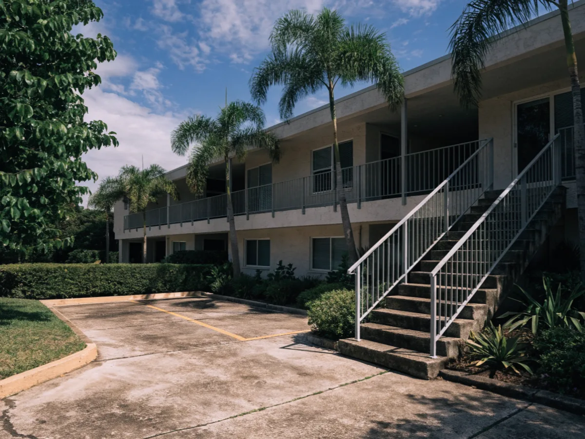 A two story condominium court a few blocks from campus in Davie, an exterior stair up to an open walkway and shared parking in front of the units