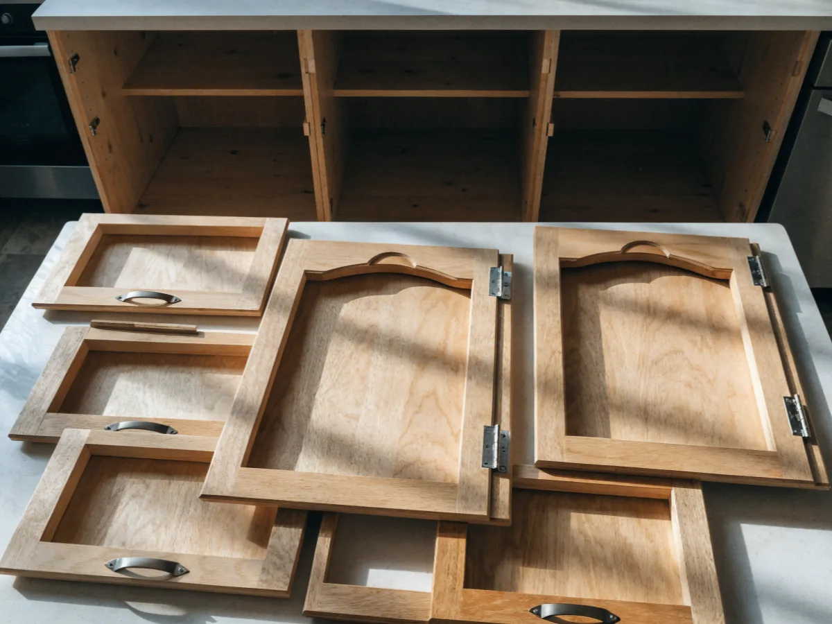 Cabinet doors and drawer fronts from a 1990s west Davie kitchen laid out on the counter with their hinges and pulls still attached