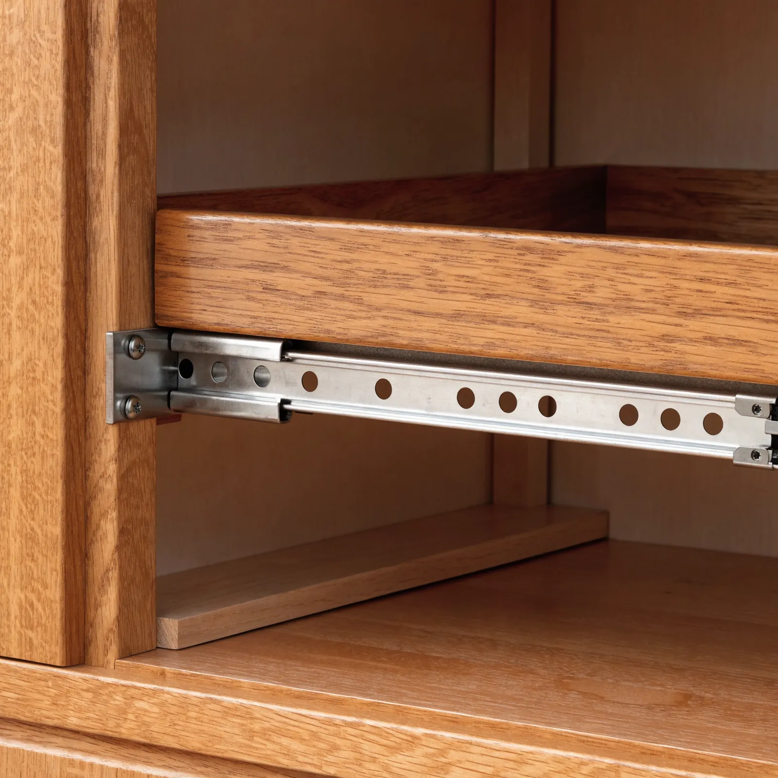 A wood pull-out tray on full-extension side-mount slides, drawn out of a face-frame base cabinet with the rear mounting bracket visible inside the box