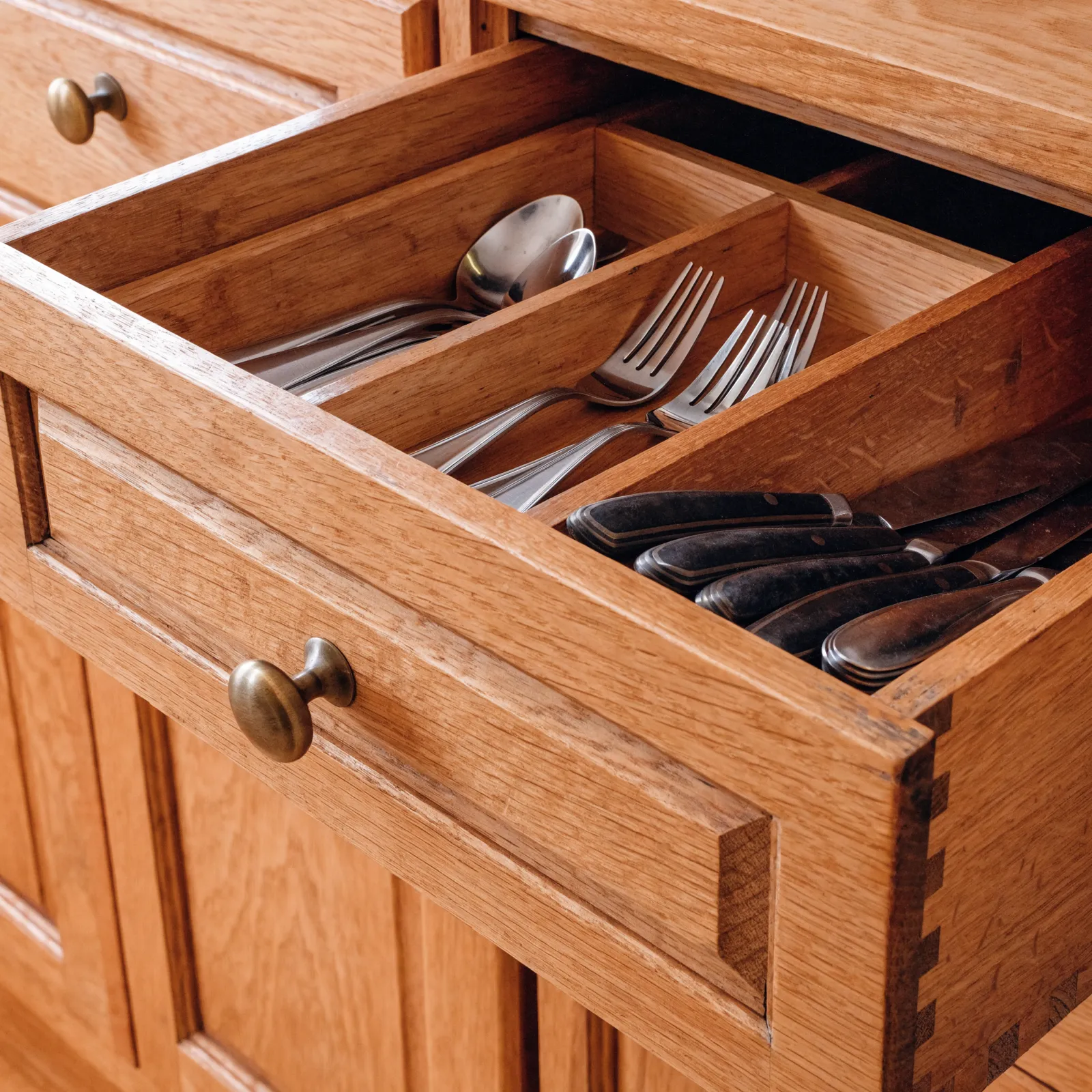 A fitted insert in an existing kitchen drawer, cutlery in the front compartments and a flat knife section behind, the drawer front unchanged