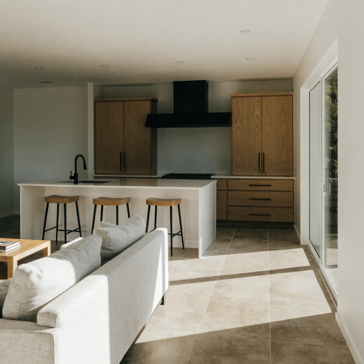 The island seen from the living room side of a Davie house, the sink facing the room and three stools tucked under the counter overhang