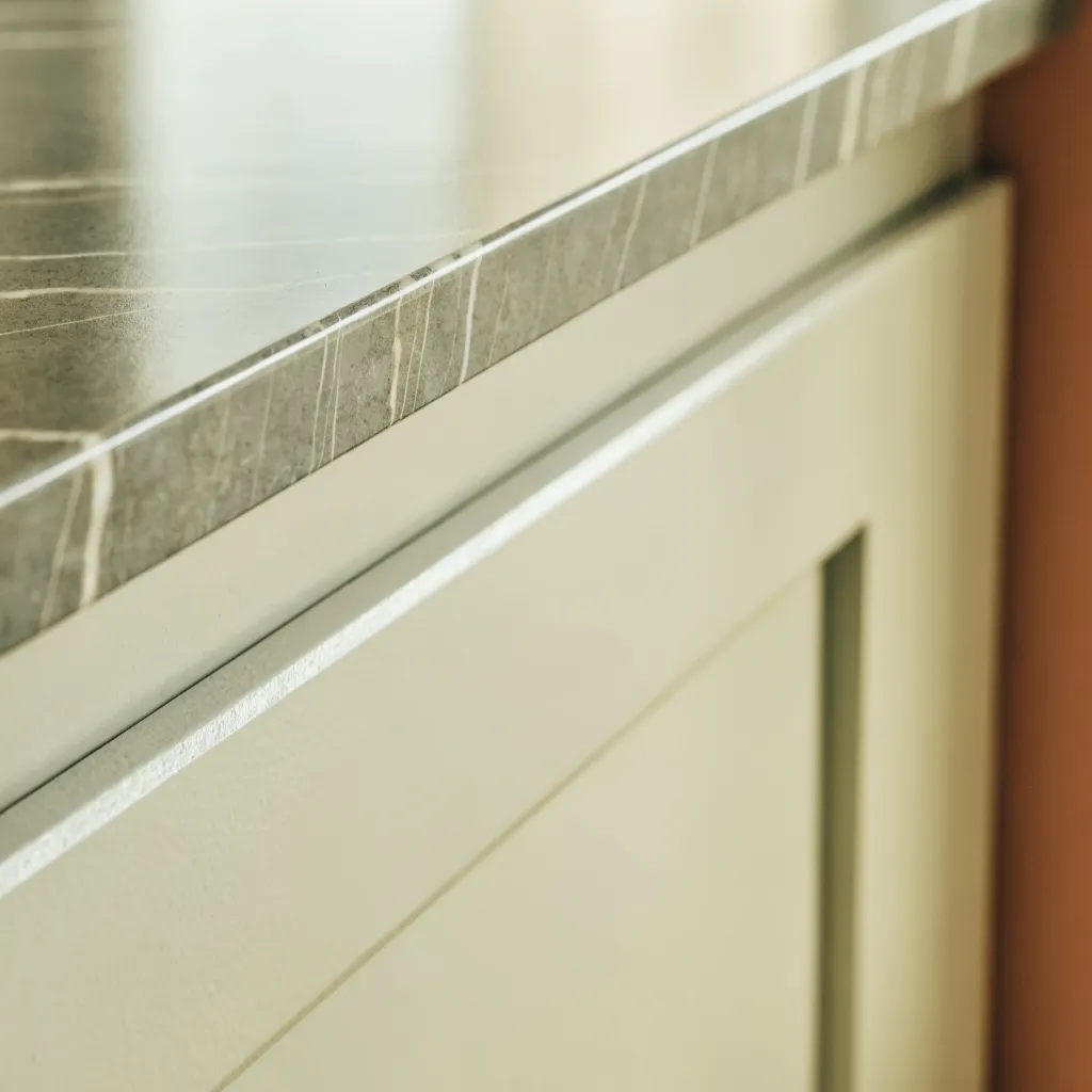 The 12 mm squared edge of a porcelain countertop slab above a shaker cabinet front