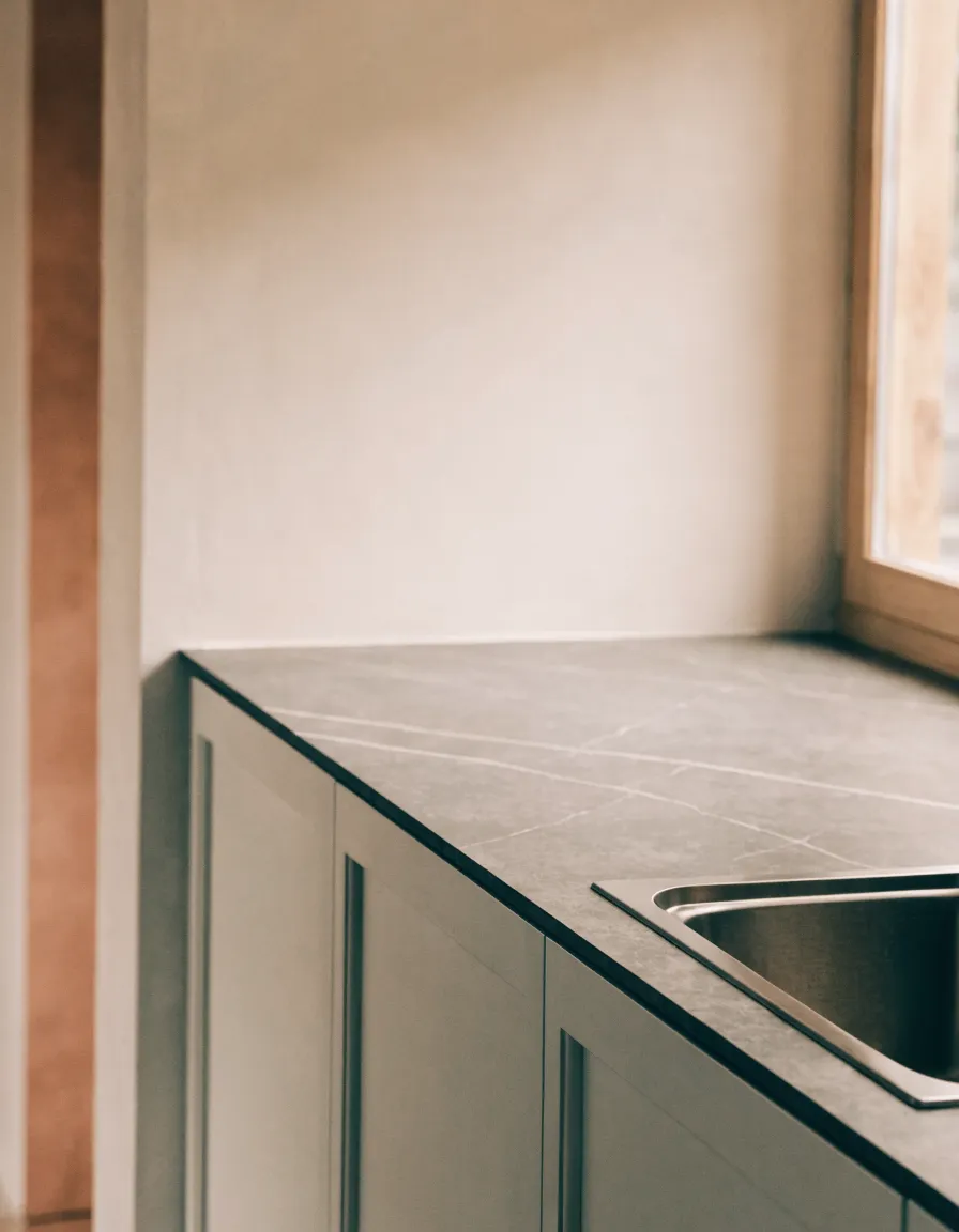 Porcelain countertop installation Davie, FL: a warm graphite porcelain run with a thin squared edge and a stainless undermount sink over pale shaker cabinets