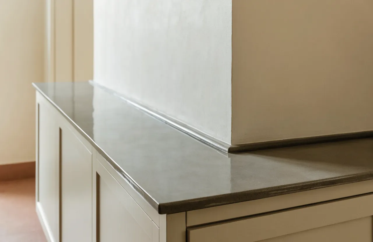 A graphite porcelain run carried around an inside corner onto the second wall with the thin squared edge continuing through the joint