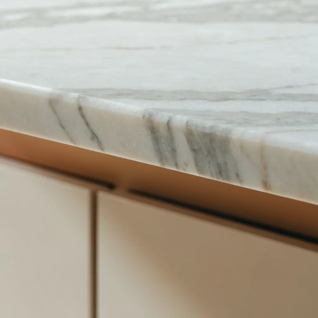 A marble slab racked under a quartzite label, the veining broad and the surface flatly matte next to a cabinet edge