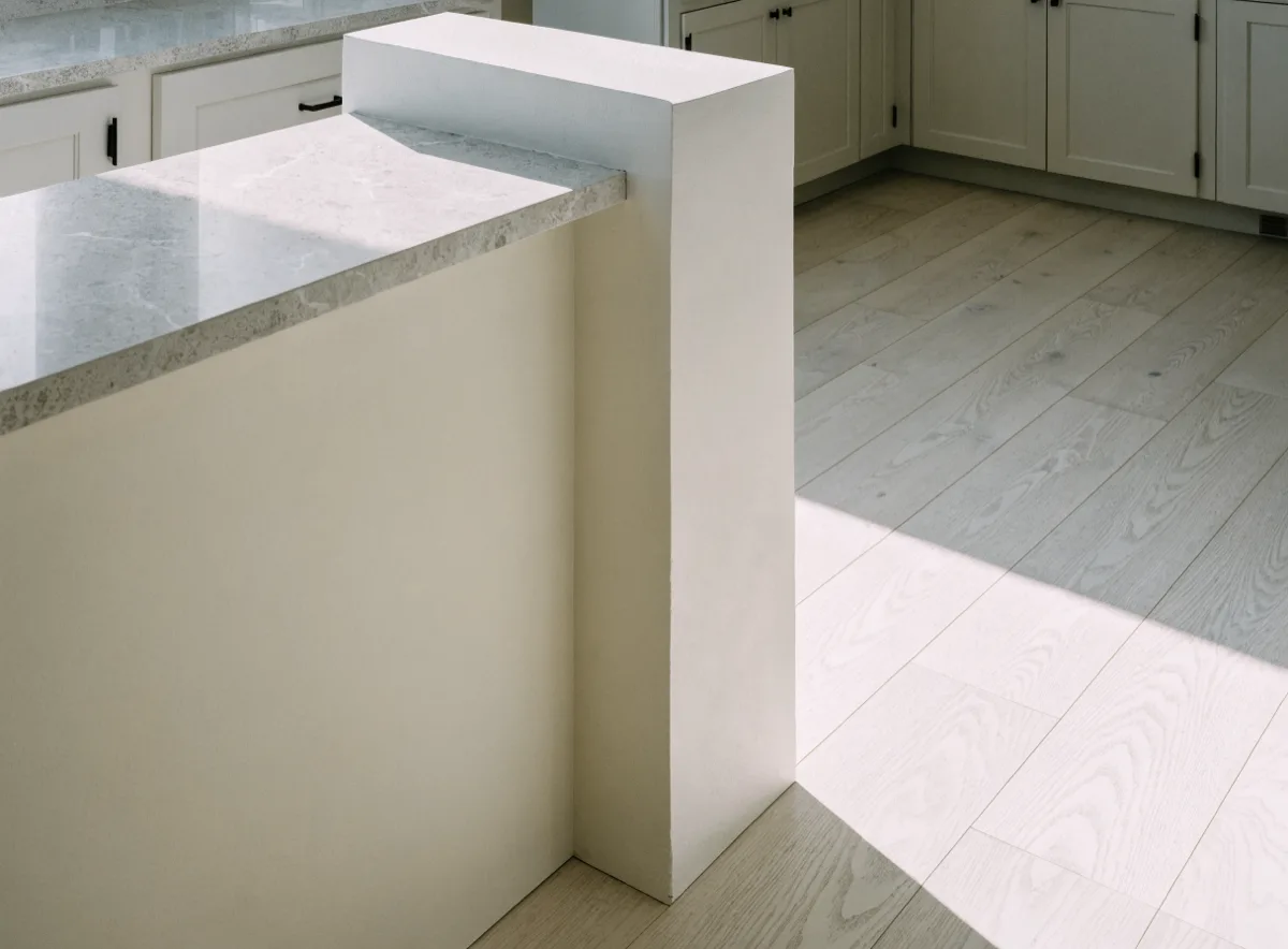 One end of the finished opening, a short square return of painted wall standing where the removed wall stopped, with the quartz counter ending just short of it